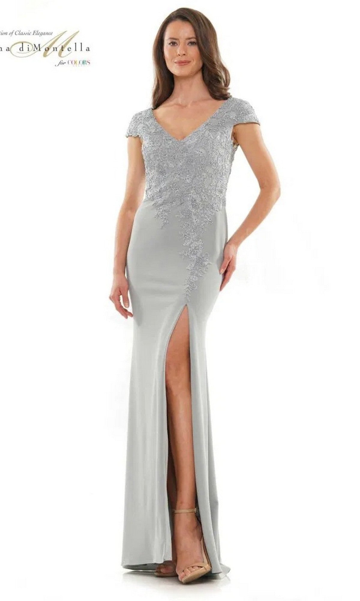 A woman wears the Rina Di Montella RD2763 long formal dress in Seaglass, featuring a sheath skirt, short sleeves, lace detailing, and a thigh-high slit. She stands against a plain white background.